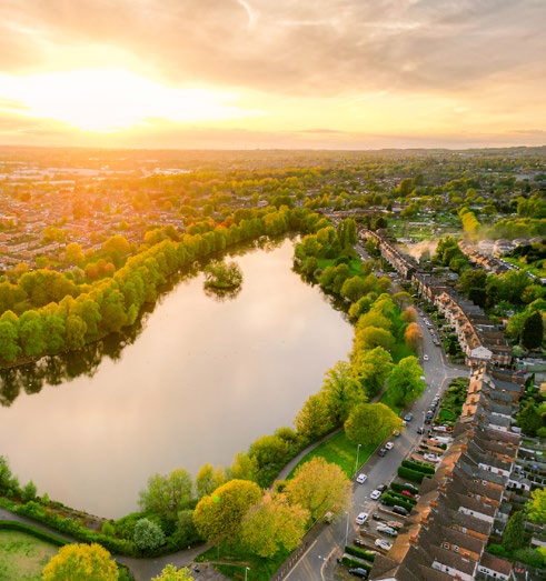 Aerial view of a lake surrounded by mature deciduous trees and suburban homes